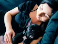 Una mujer duerme con su cachorro de bulldog francés negro. Mi perro se tumba a mi lado, ambos en un abrazo tierno y reconfortante.
