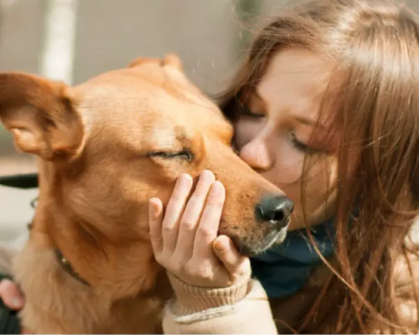 Una chica besa a su perro, que cierra los ojos, sintiendo el amor. Es la pura felicidad que siente un perro cuando le das un beso.
