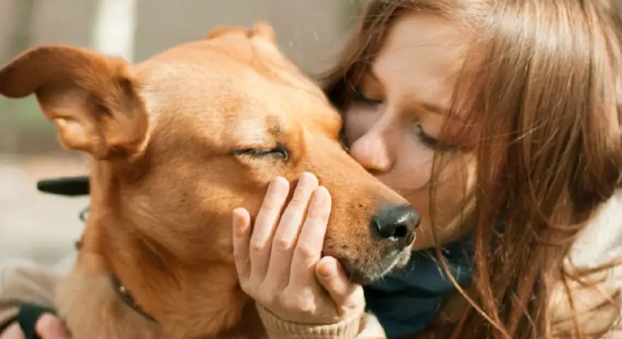 Una chica besa a su perro, que cierra los ojos, sintiendo el amor. Es la pura felicidad que siente un perro cuando le das un beso.